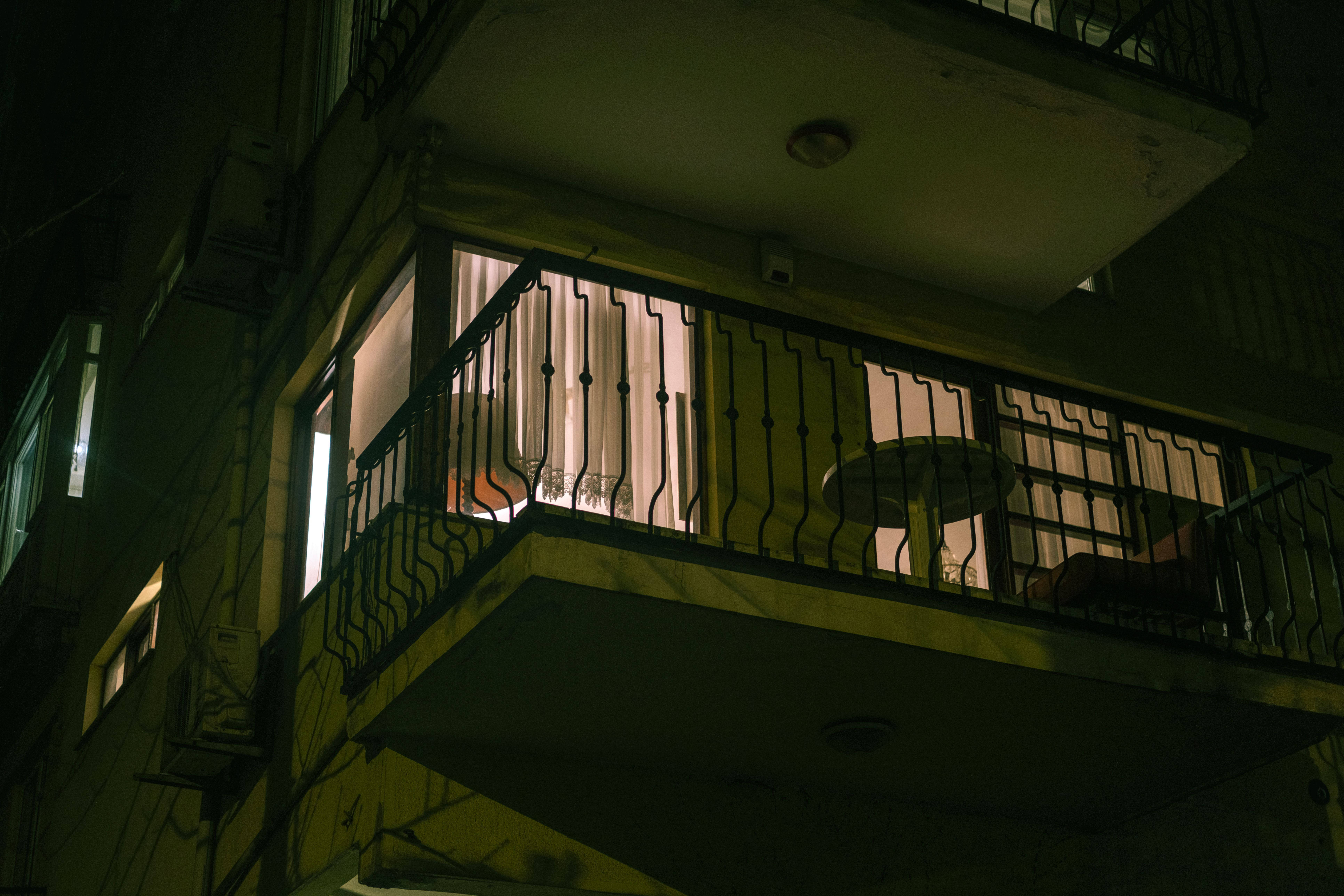A dimly lit urban balcony with chairs and a table at night