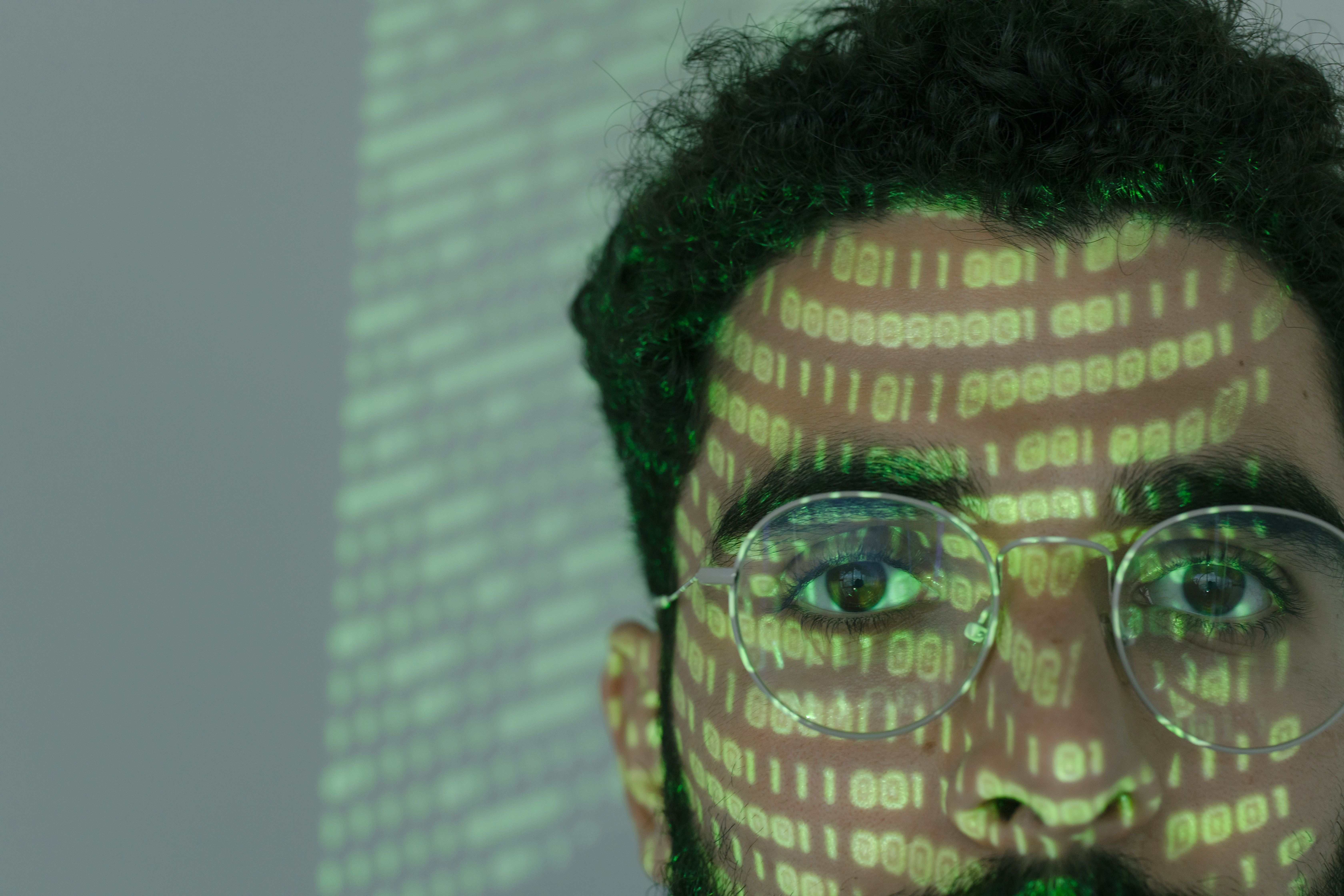 Binary code projected across a person’s face, representing hidden identity and technical indicators used in cyber investigations.
