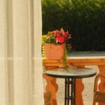 Cozy outdoor patio with potted flowers, wicker chairs, and a round table