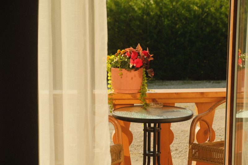 Cozy outdoor patio with potted flowers, wicker chairs, and a round table