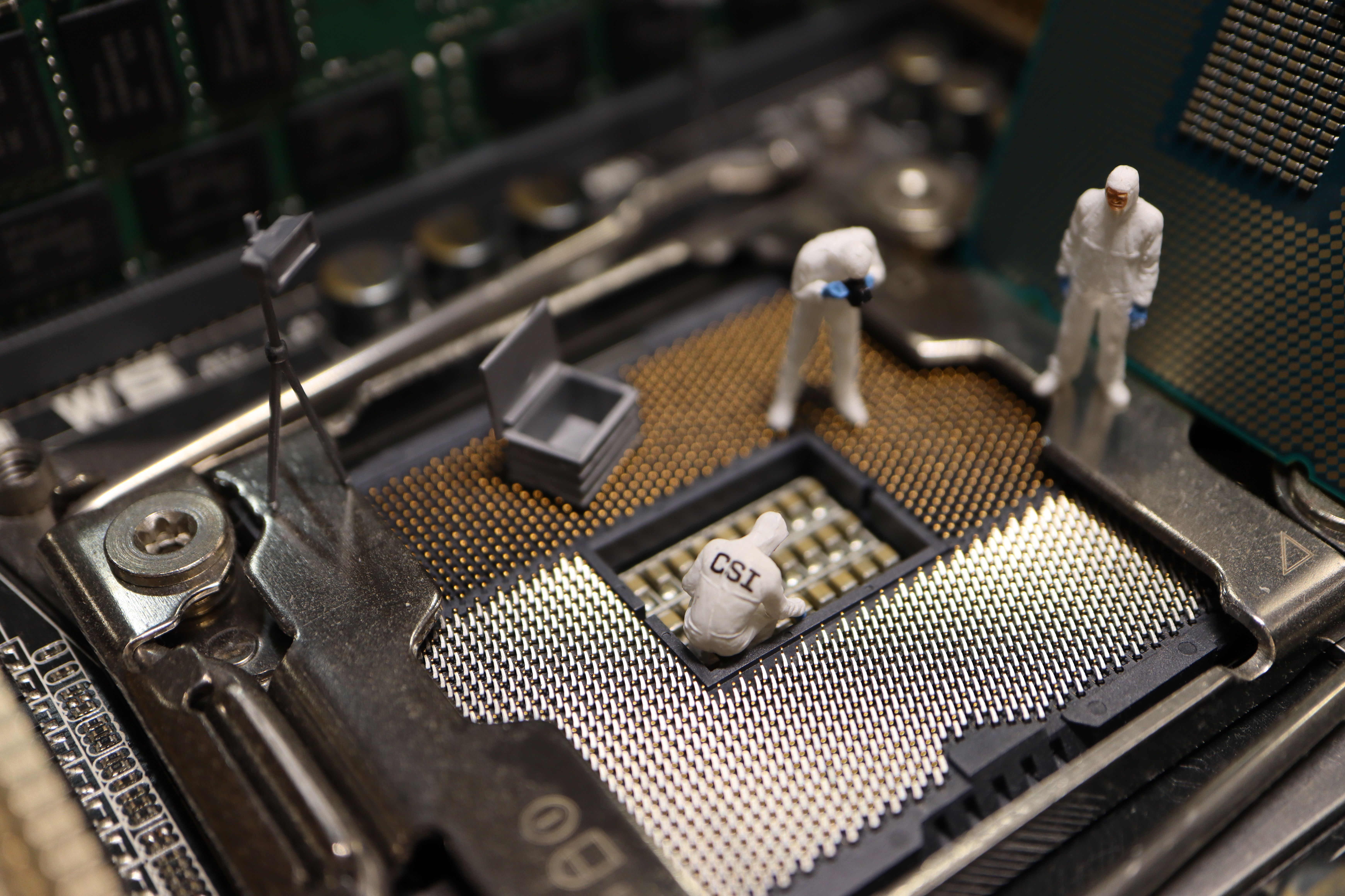 Tiny investigators examining a computer processor, symbolizing digital forensics and threat actor attribution.