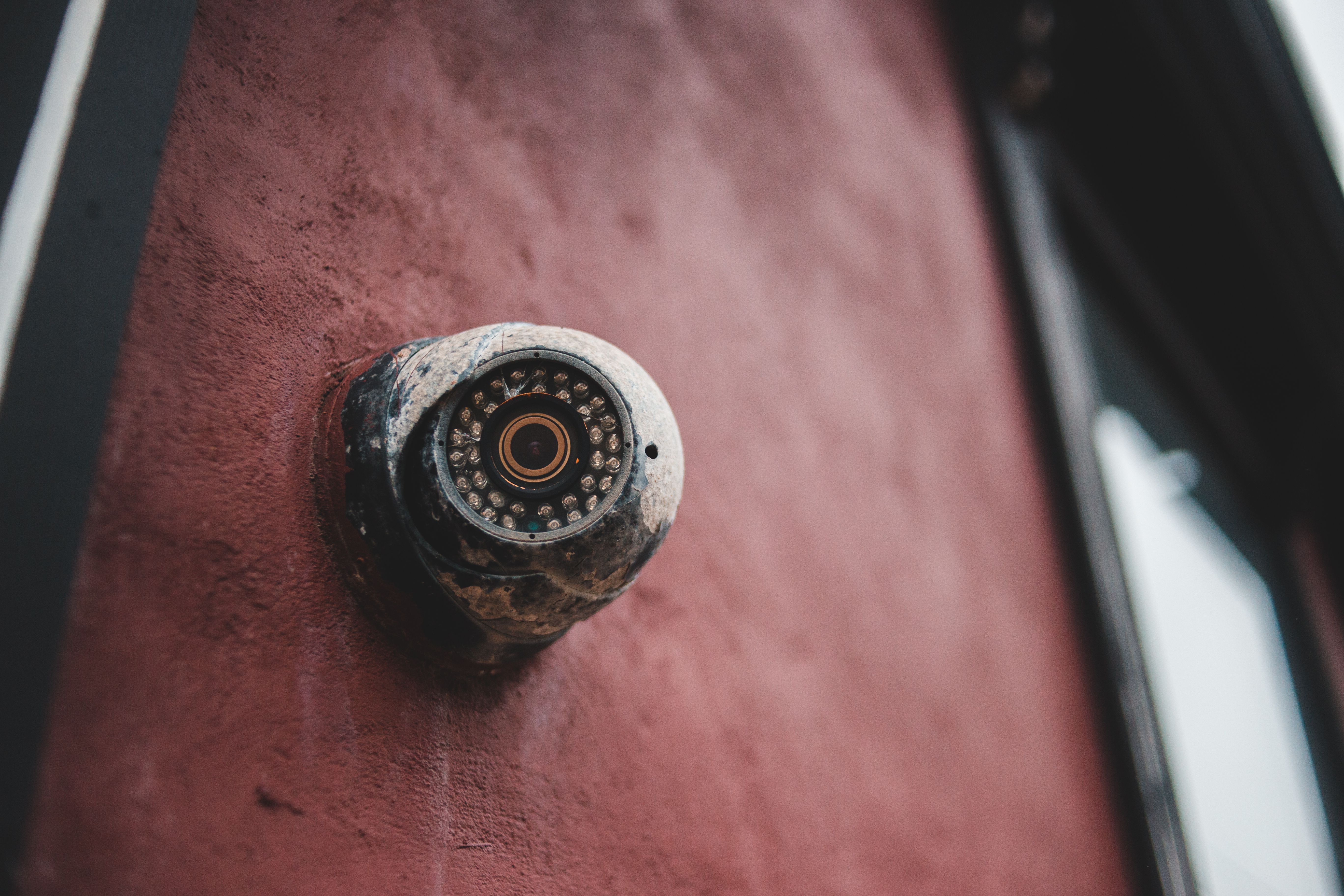 Exterior security camera mounted on a house wall near an entry point