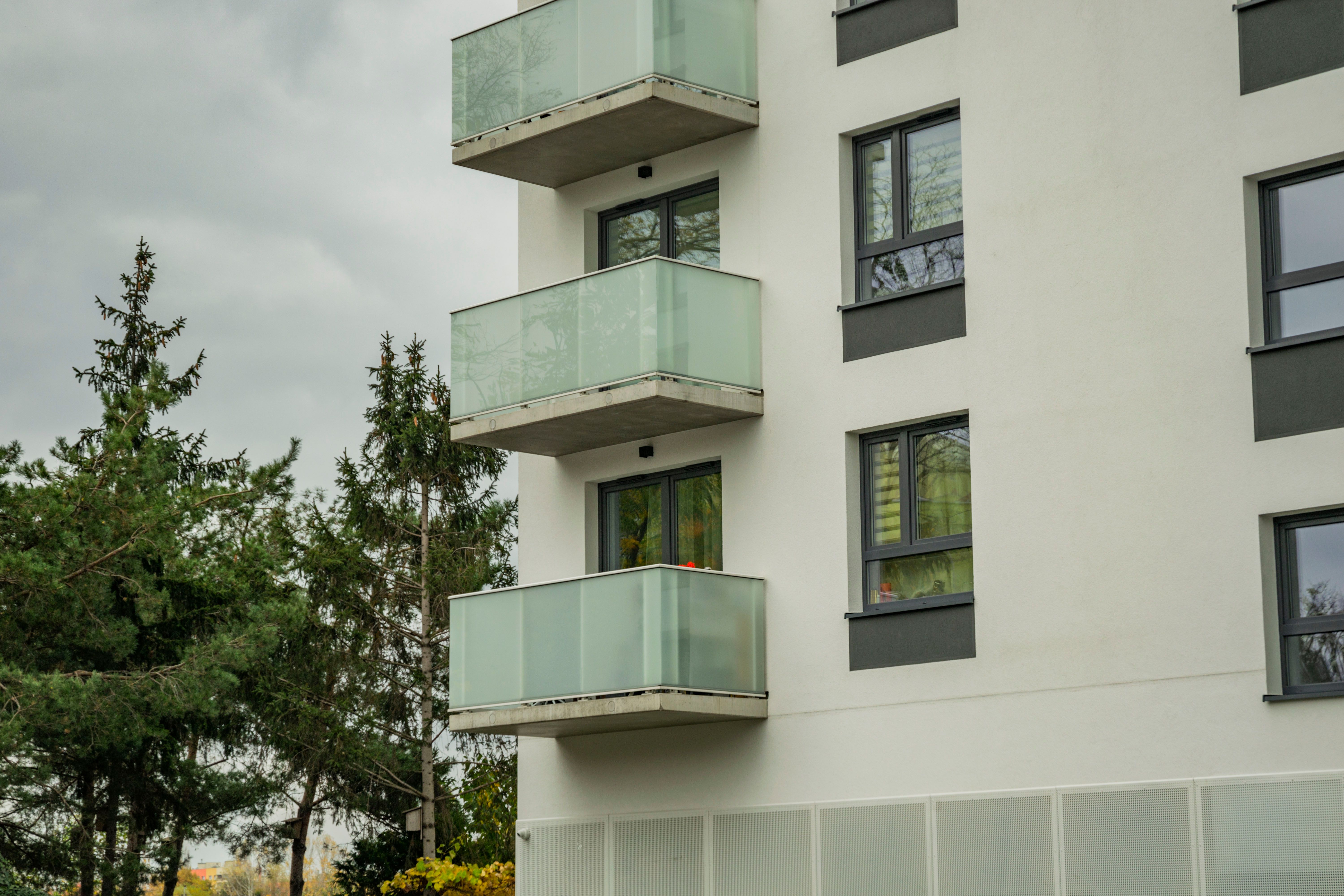 Contemporary apartment building with glass balconies and green surroundings