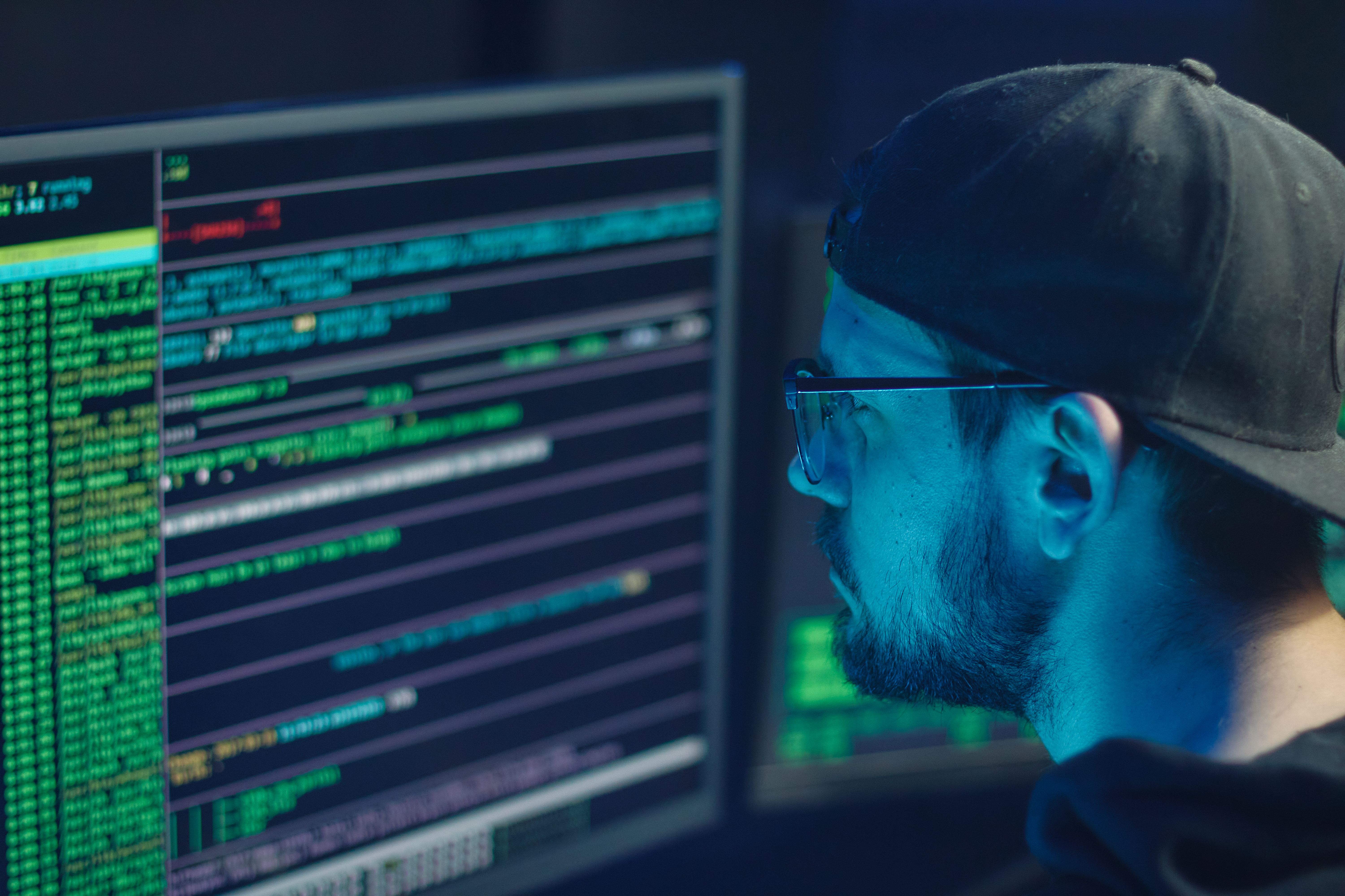 Cybersecurity expert examining code across multiple monitors in an operations office.