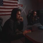 Two analysts reviewing data in a dimly lit cybersecurity operations setting.