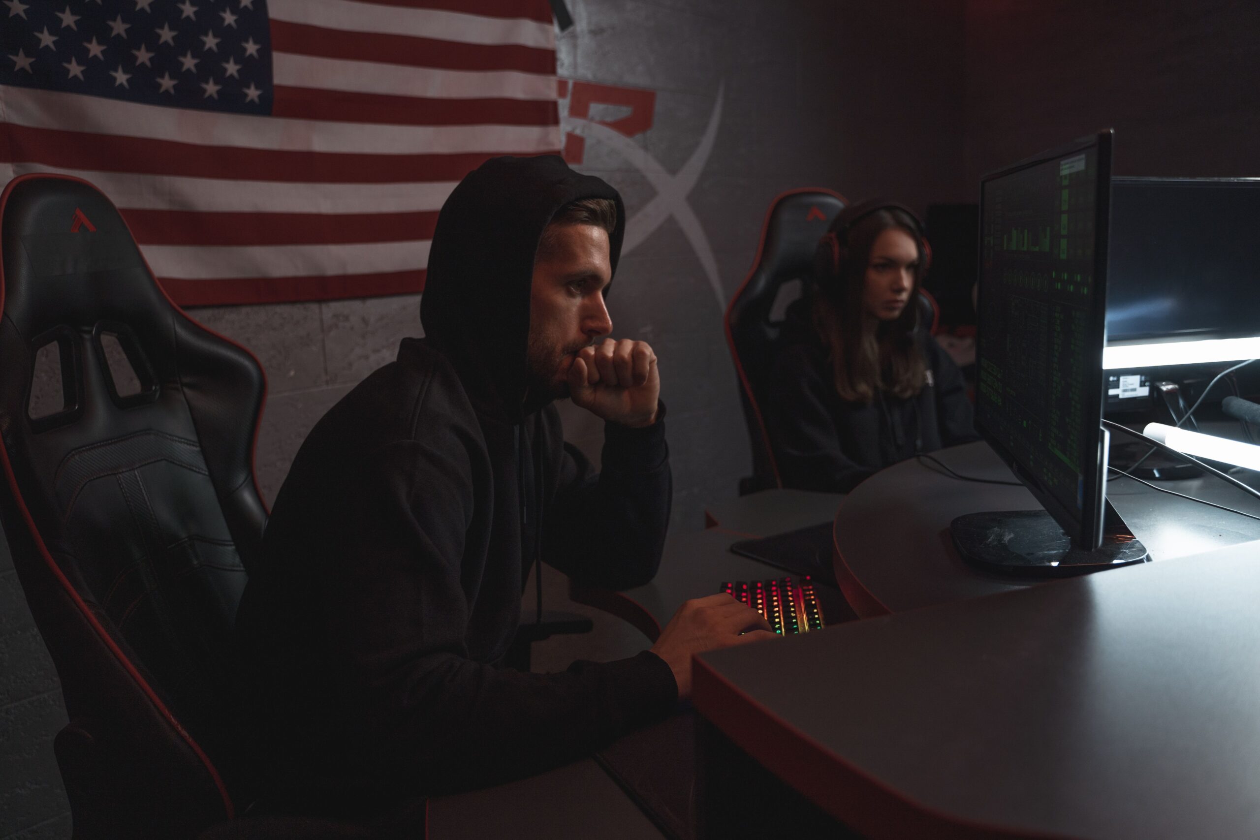 Two analysts reviewing data in a dimly lit cybersecurity operations setting.